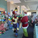 Children watch the Grinch and performers in Mario costumes high five at the Family Holiday Celebration