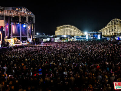 A vast audience listens to a live concert at night during the Barefoot Country Music Fest.