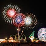 Night sky with fireworks bursting over carnival rides like ferris wheel and rollercoaster in the wildwoods NJ
