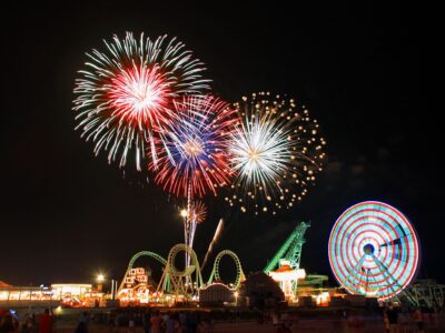 Night sky with fireworks bursting over carnival rides like ferris wheel and rollercoaster in the wildwoods NJ