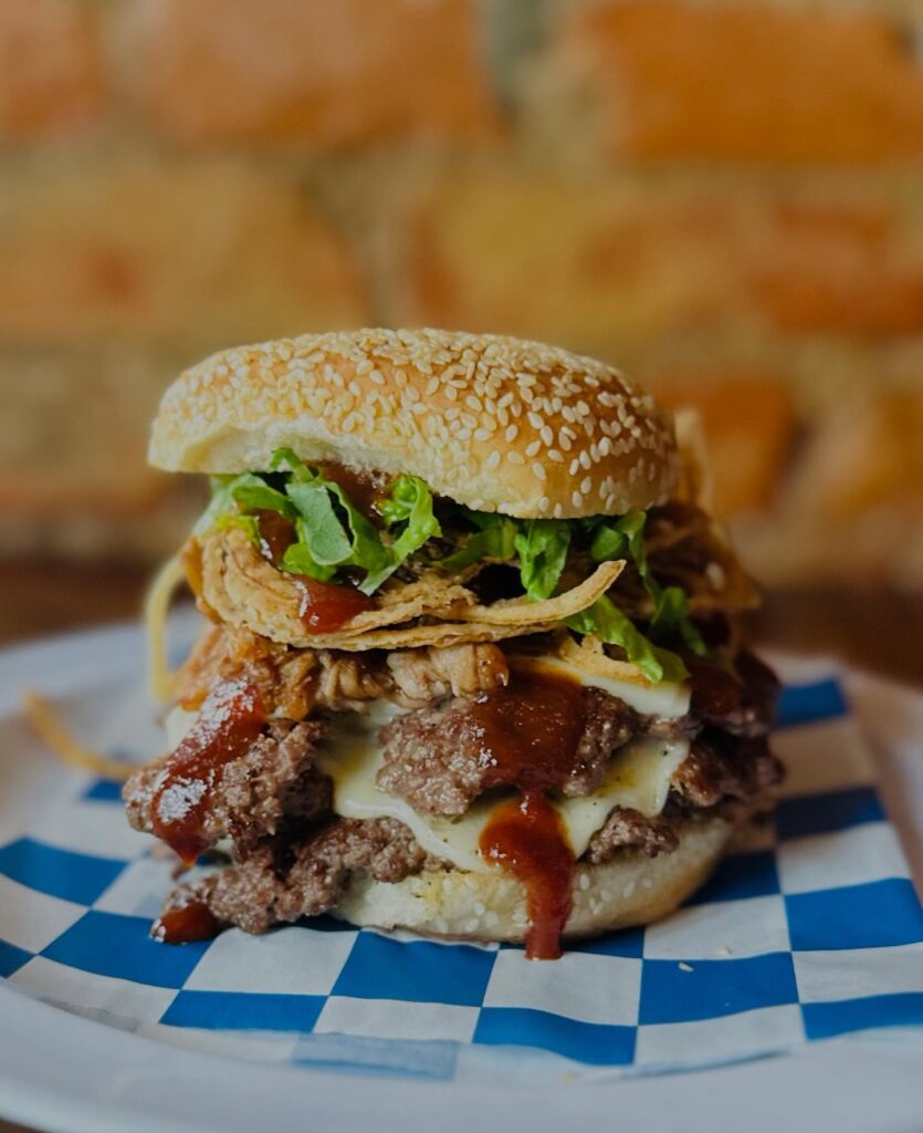 A big burger sitting on a blue and white piece of parchment paper from The Rook Wildwood